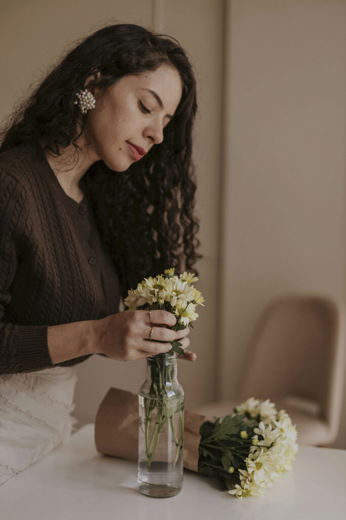 Woman arranging yellow flowers in a glass vase